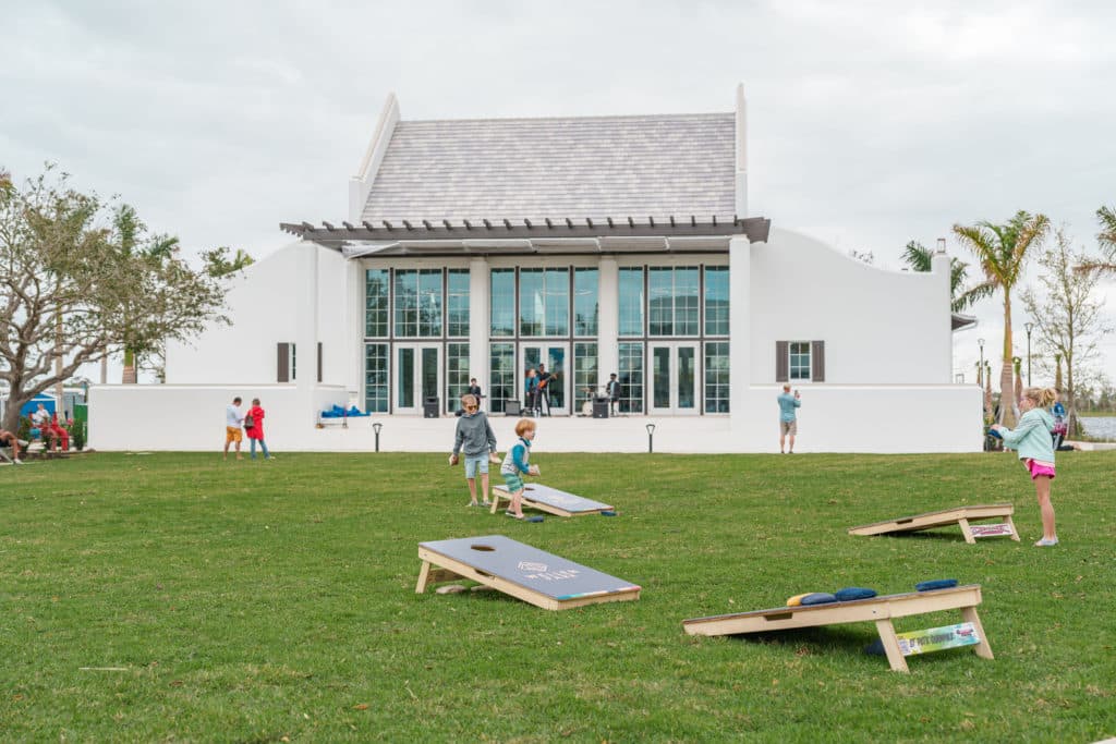 Large white building (Solis Hall) and an open lawn (the Great Lawn) filled with kids and cornhole boards
