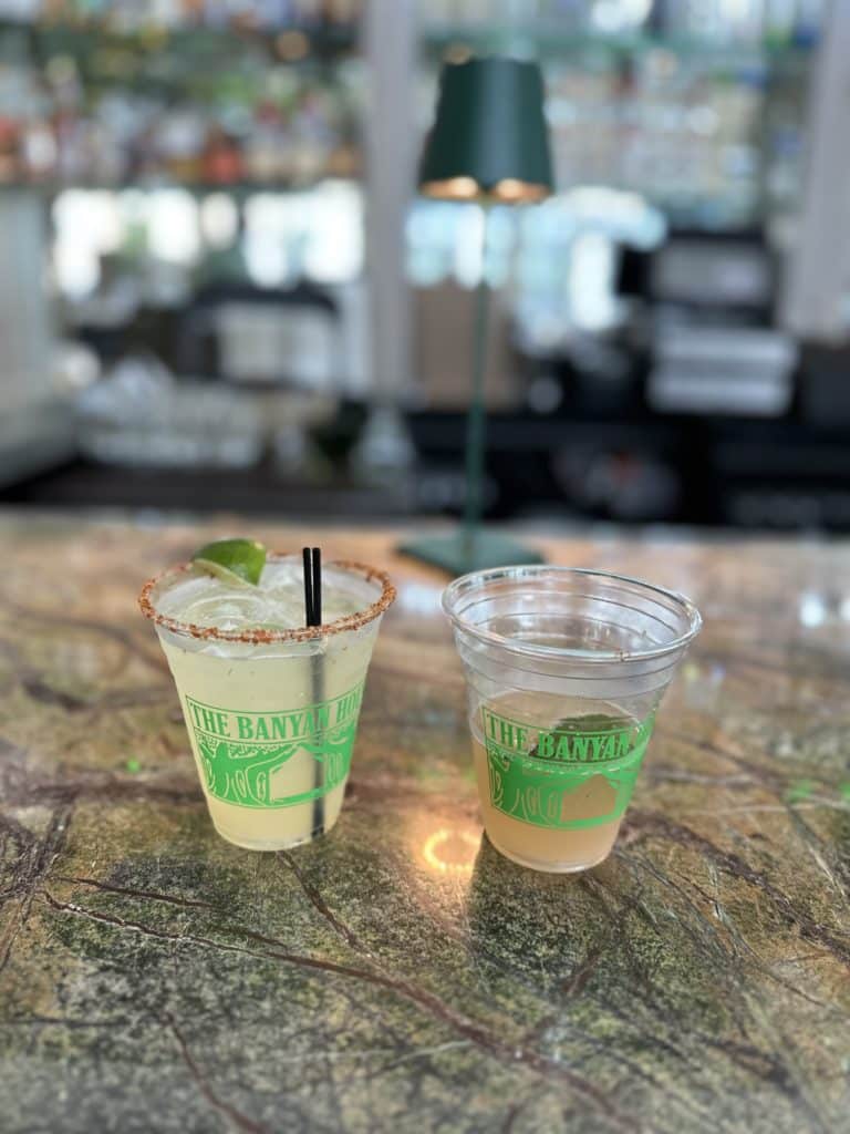 Two cocktails in plastic cups that read: The Banyan House
