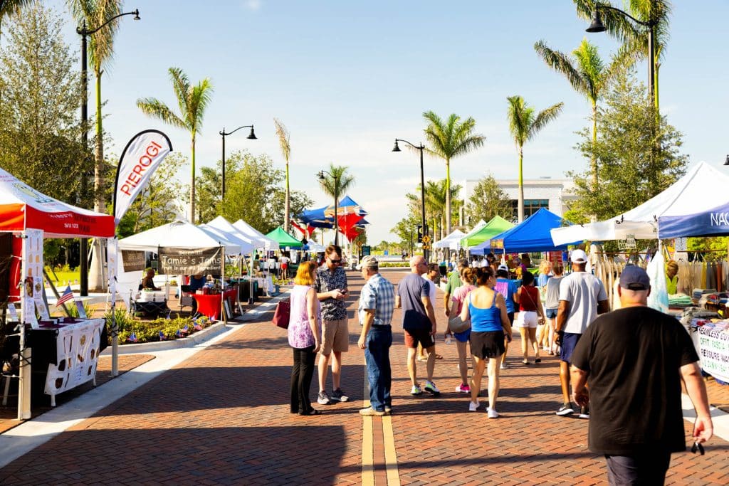 People are walking through the Fresh Harvest Farmers Market in Downtown Wellen Park.